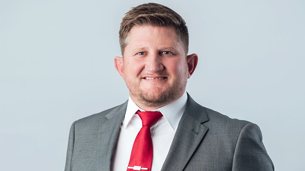 Willem Strydom in grey suit with red tie, smiling