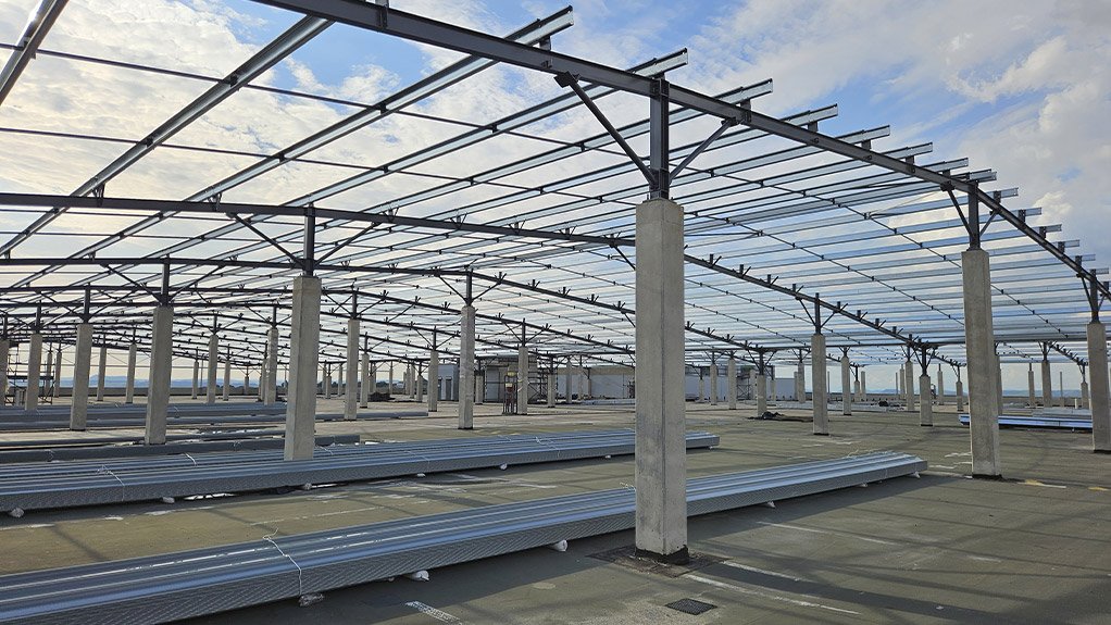 Structural steel elements being installed atop the concrete columns, forming the framework for the new rooftop structure at Fourways Mall