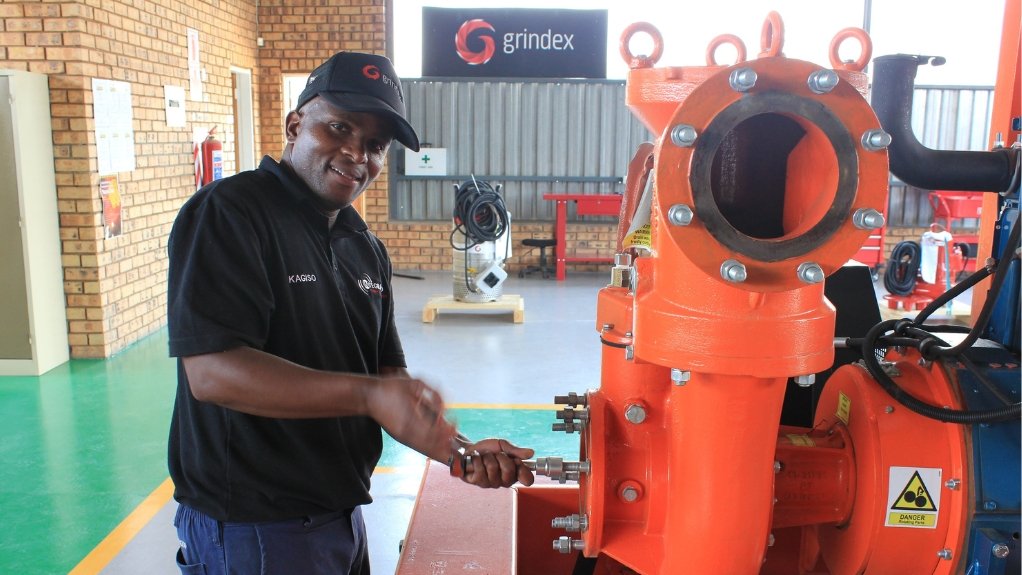 A technician working on an orange pump in a service centre