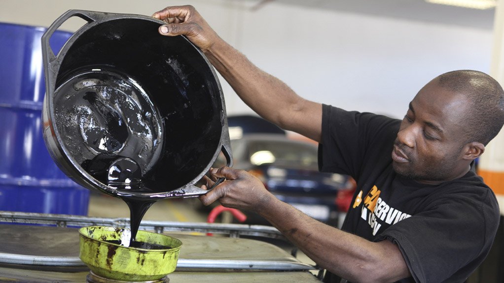 An image of a man pouring used oil into a container 