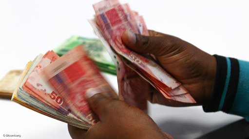 Hands holding South African banknotes