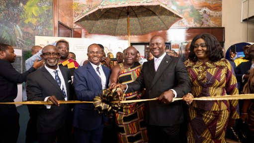 Men and women in suits and traditional Ghanaian clothing on the stage all hoping a ribbon ready to cut it