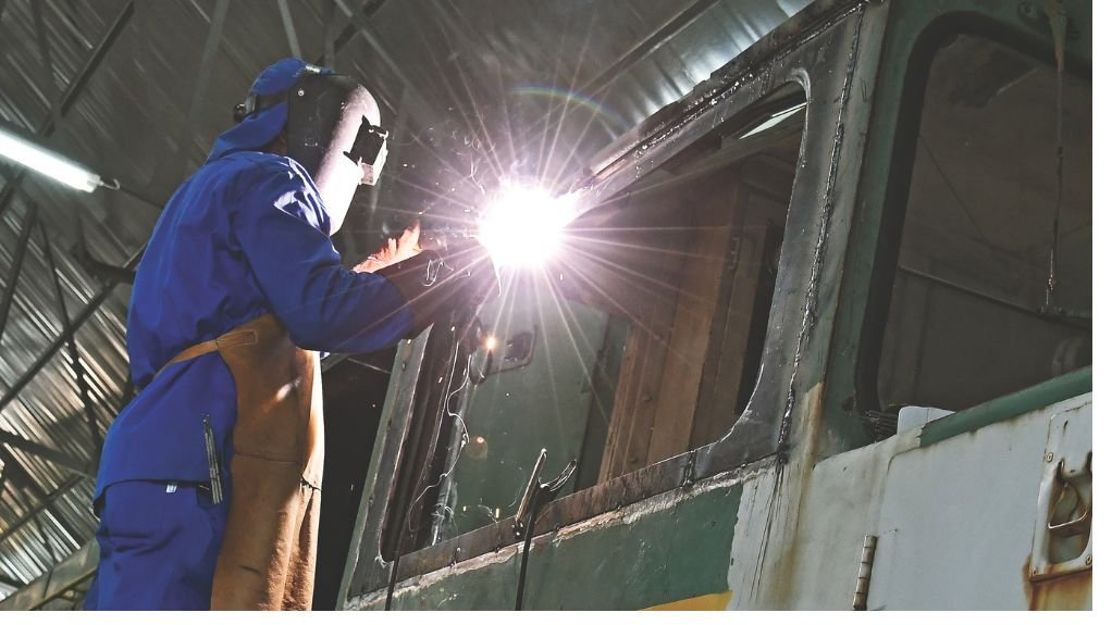 A worker welding a section on a train. 
