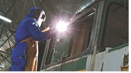 A worker welding a section on a train. 