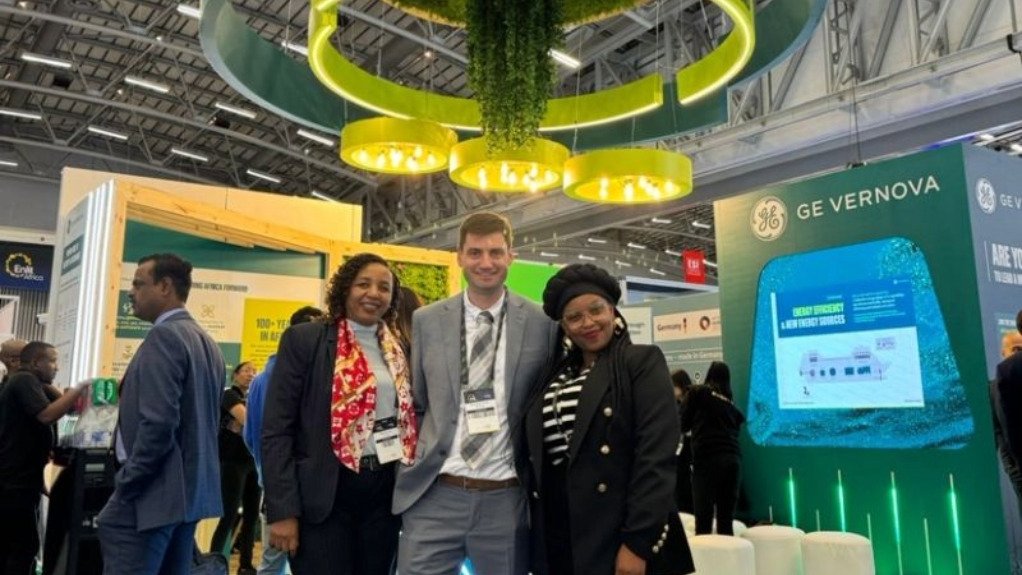A picture of three GE Vernova executives stood in fornt of a Stand at an expo.