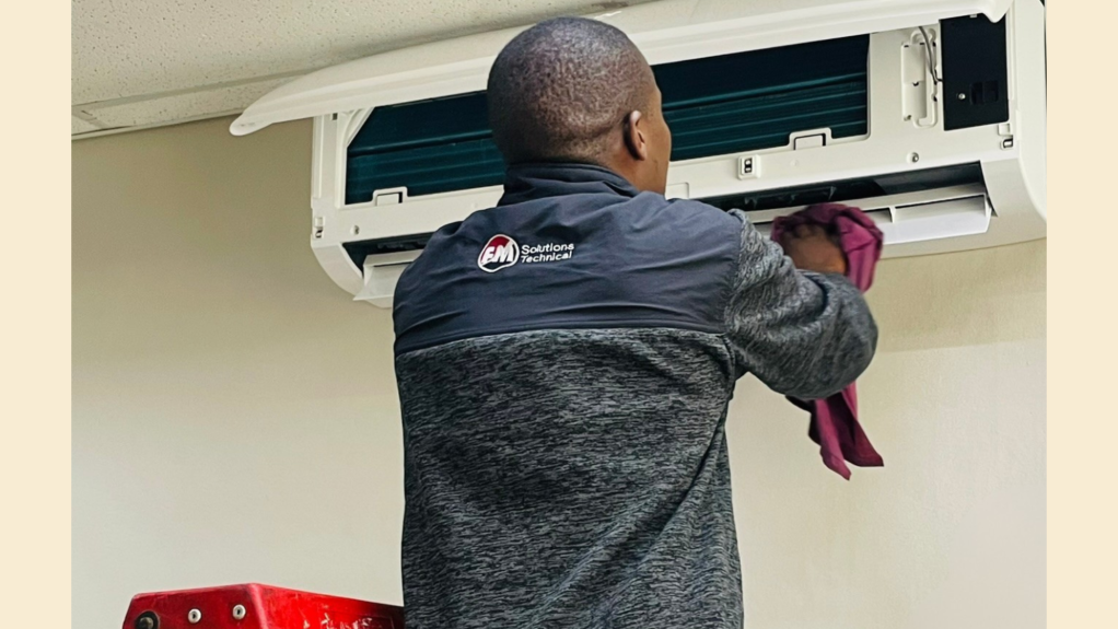 An image of an FM Solutions technical team member working on an HVAC component