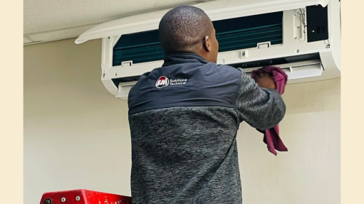 An image of an FM Solutions technical team member working on an HVAC component