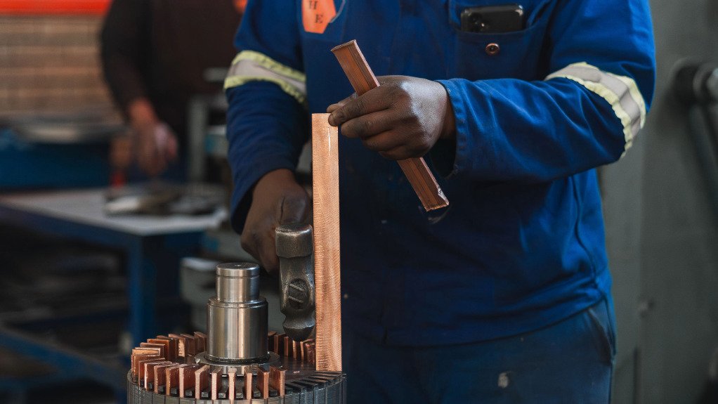 a man hitting a copper bar into a rewound motor