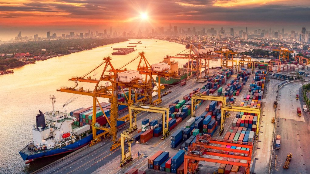 An aerial view of cranes at a harbour loading a ship at sunset