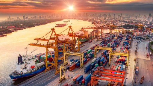 An aerial view of cranes at a harbour loading a ship at sunset