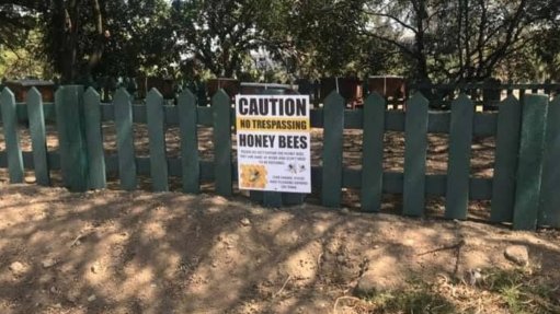 An image of a sign which reads 'caution honey bees'