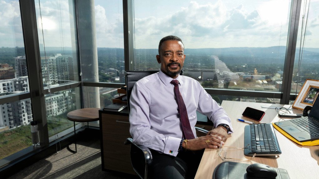 a picture of Mzila Mthenjane Minerasl Council CEO sat at his desk in front of a window overlooking Rosebank