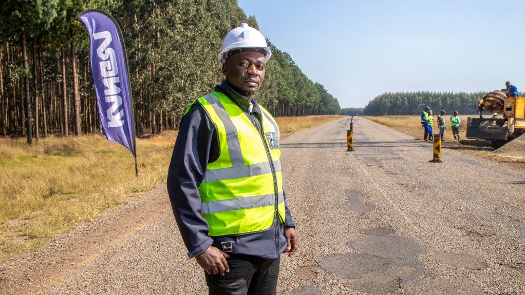 Kangra stakeholder relations manager Mpfuneni Mulaudzi on a road in front of the mine with a Kangra flag in the background