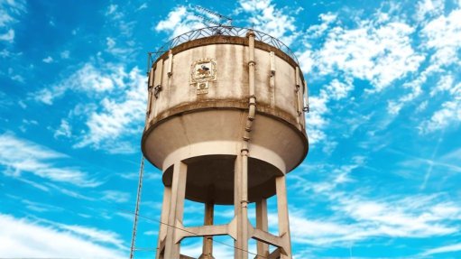 A water tower against a blue sky with white clouds. 