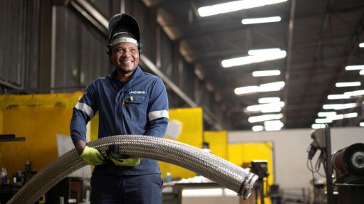 An image of a factory worker with an industrial hose