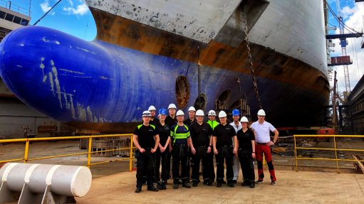 A group of engineers at the fore of a large cargo ship 