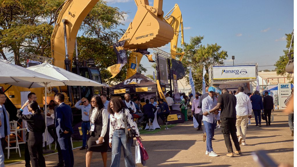 An outdoor expo of yellow machines with people walking around