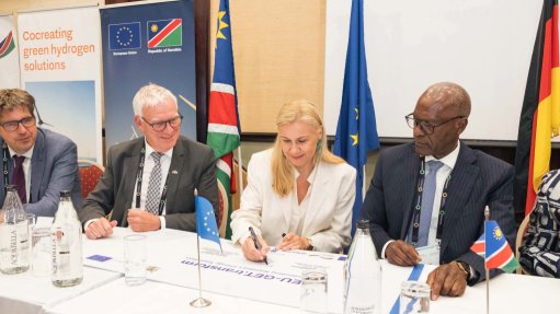 dignitaries form various companies sat at a table signing a declaration