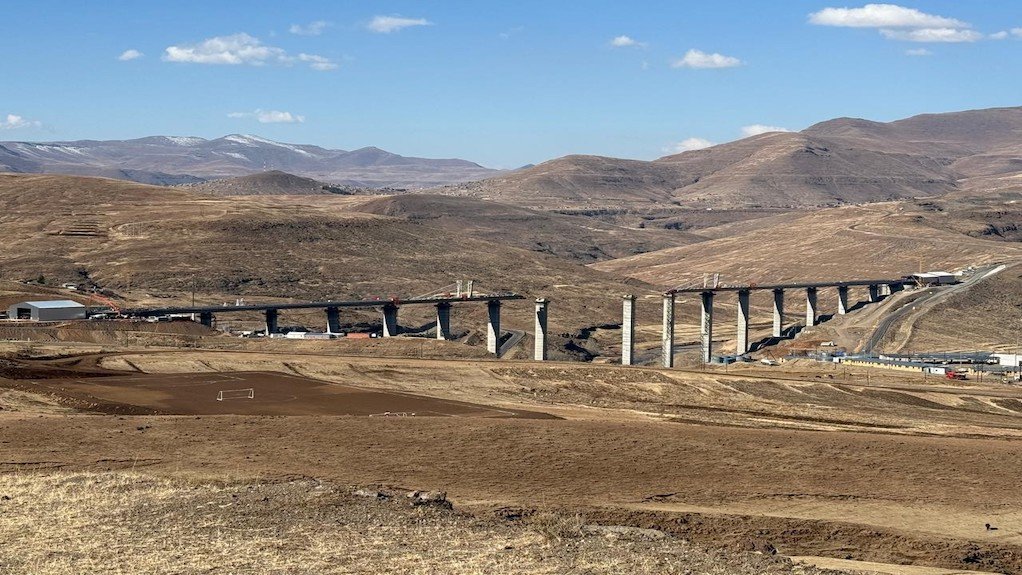 The Senqu Bridge against the backdrop of the Maluti Mountains, with the towering piers and near complete deck in full view.