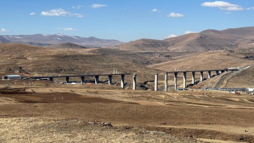 The Senqu Bridge against the backdrop of the Maluti Mountains, with the towering piers and near complete deck in full view.