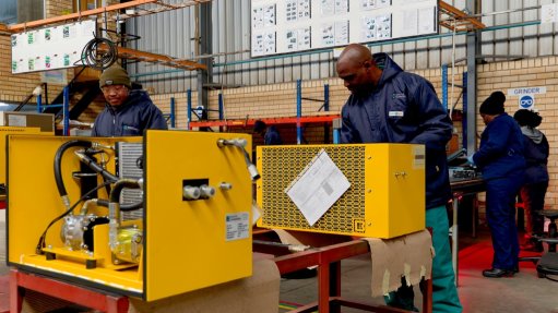 Yellow HVAC units assembled on workshop floor, workers blue overalls