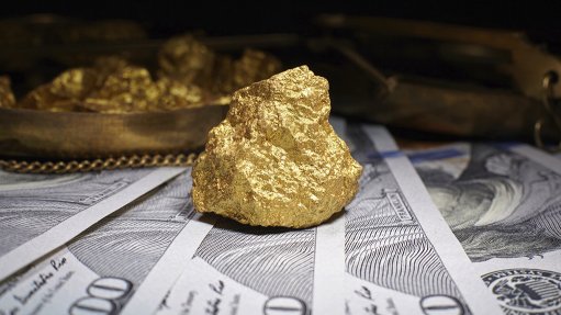 A gold nugget resting on dollar banknotes
