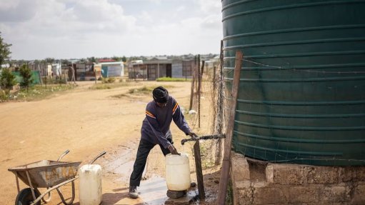 A man tapping water from a water storage vessel at a remote location