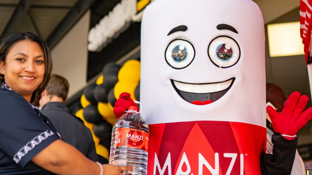 the MANZI Water mascot with a bottle of water next to a lady