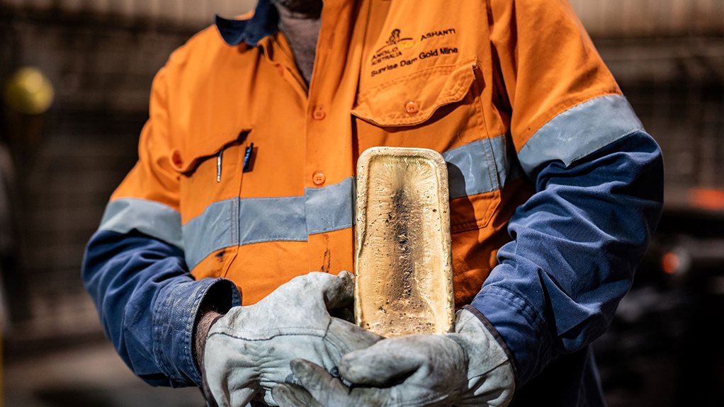 A sunrise dam employee holding a gold bar