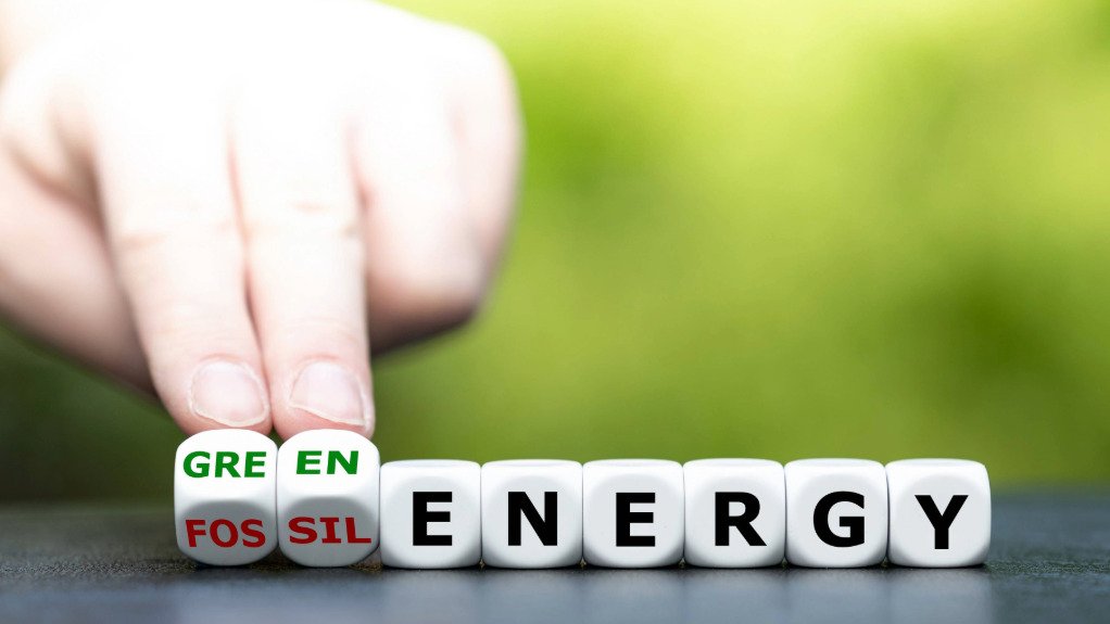 An image depicting a hand changing letters from the words fossil fuel to clean energy