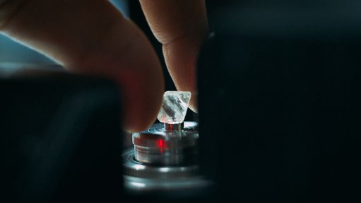 woman's hand placing diamond on small pedestal