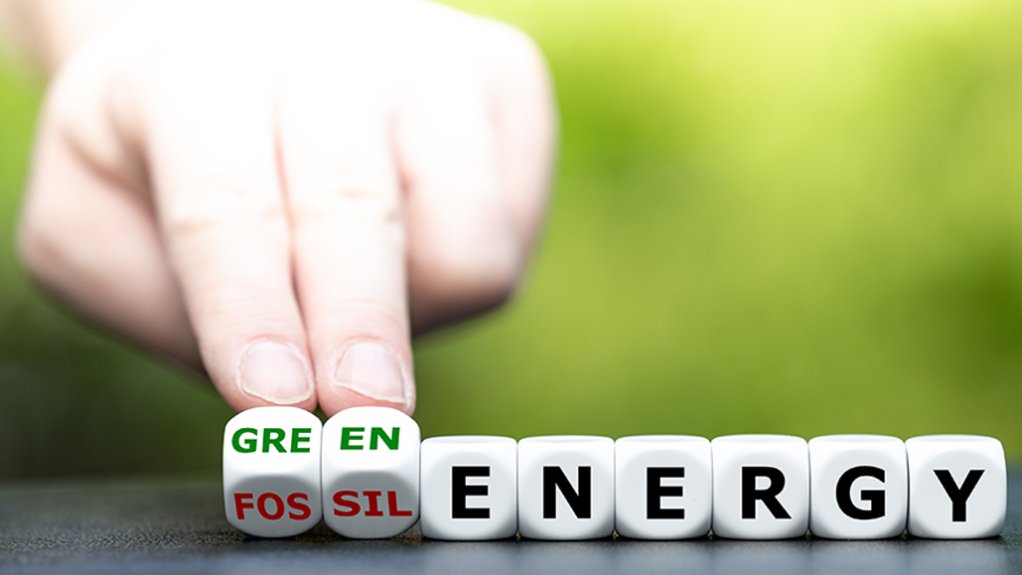 hand rolling dice that say fossil/green energy