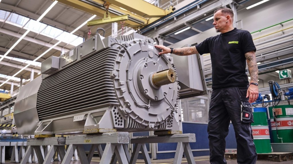 Man standing next to motor in workshop