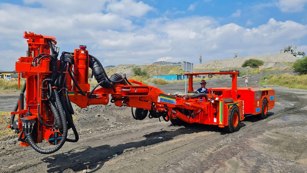 A large red mining machine being operated by a man in PPE