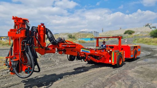 A large red mining machine being operated by a man in PPE