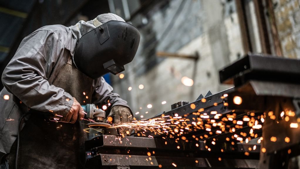Construction worker cutting steel on site. 