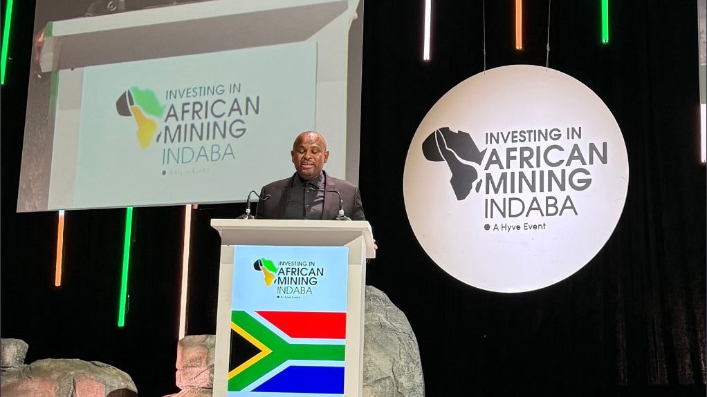 Loyiso delivering a presentation at a podium at Investing in Africa Mining indaba