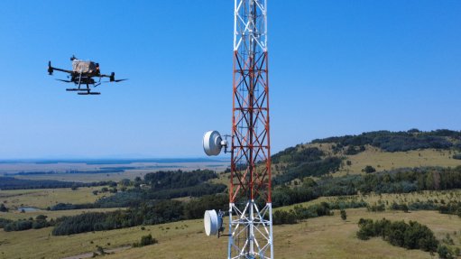 An image of a drone next to a transmission tower