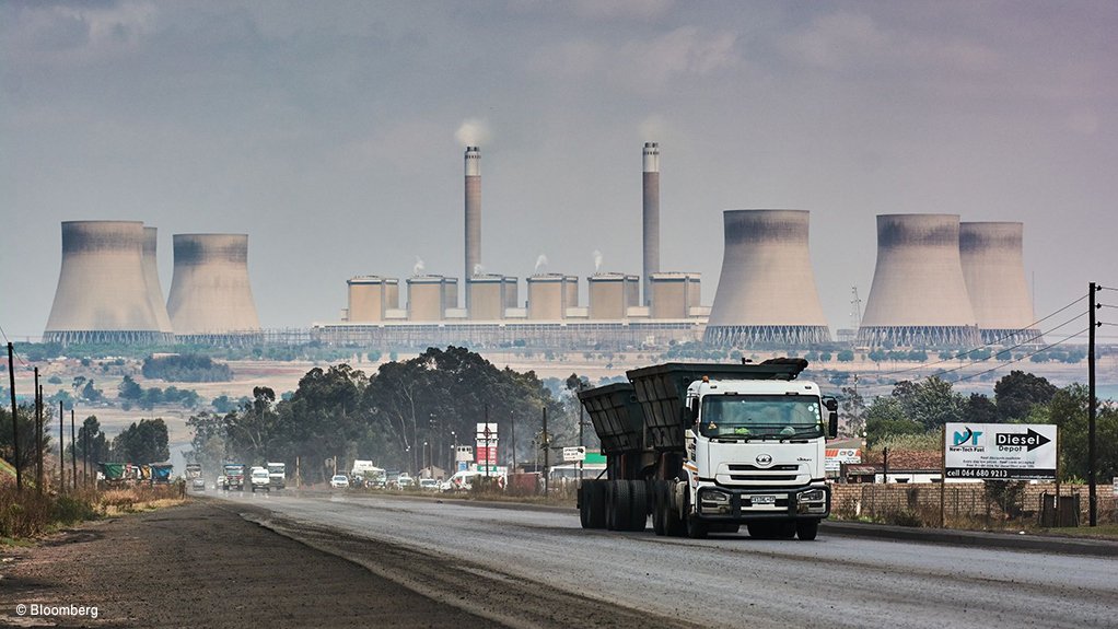 A coal transportation truck driving past a coal-fired power station