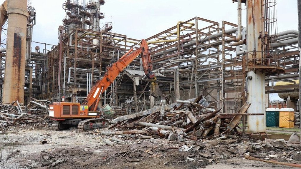 The above image depicts a crane demolishing an old plant