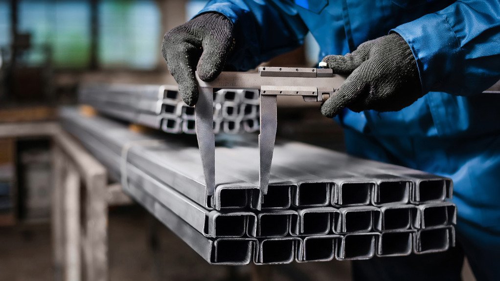 An image of a factory worker measuring a metal product 
