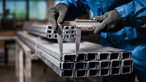 An image of a factory worker measuring a metal product 