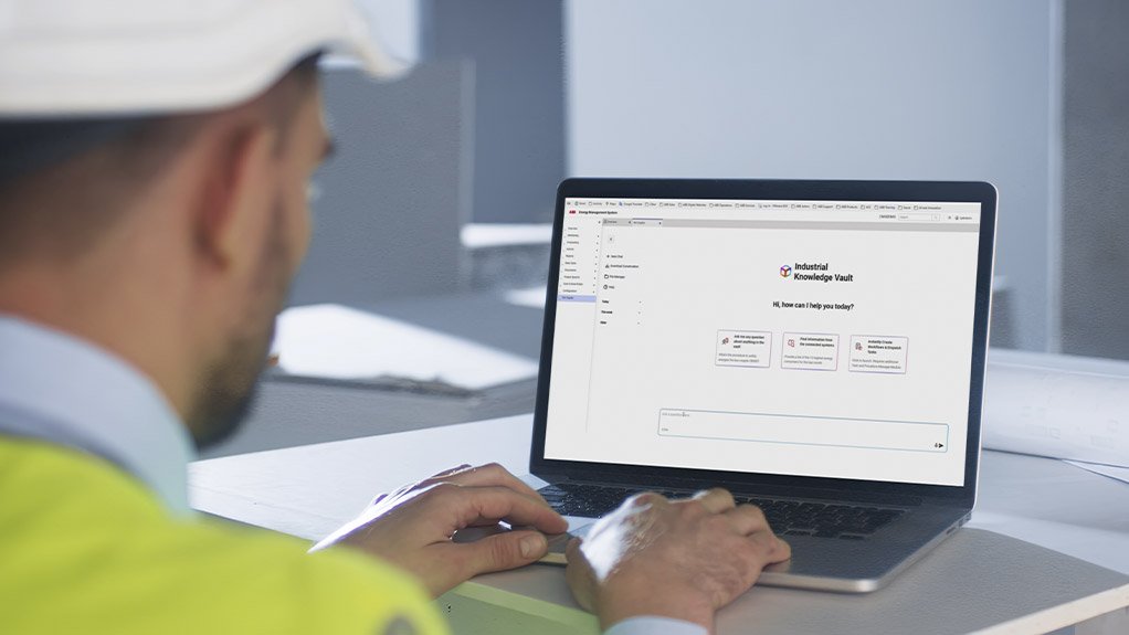 Image of an a person wearing a hardhat working on a laptop 