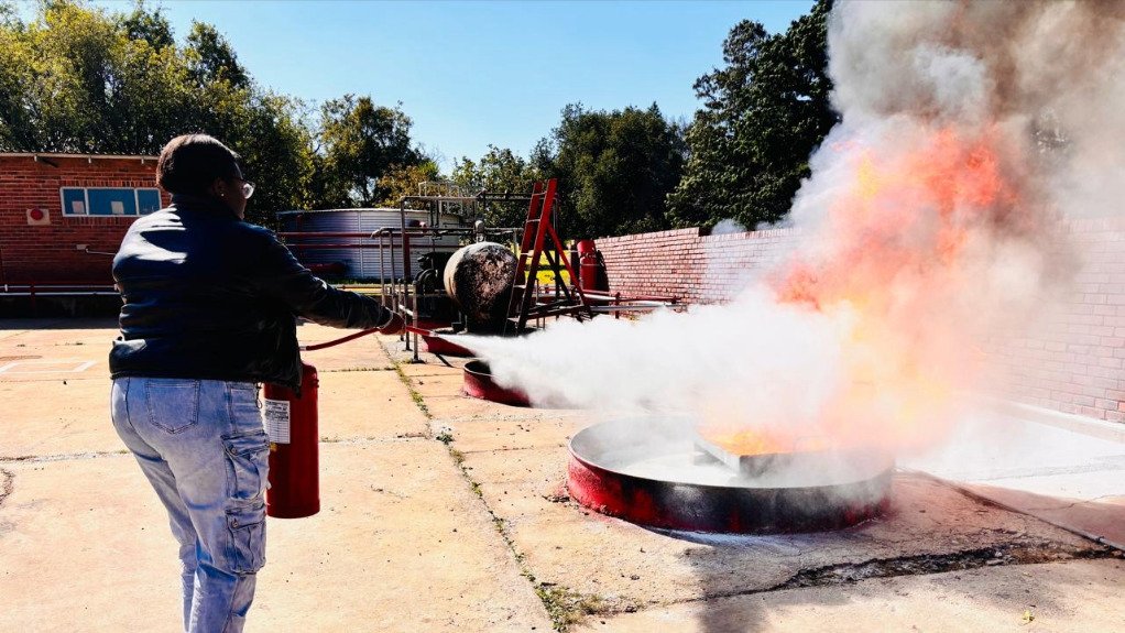 The above image depicts a fire marshal in training extinguishing a fire with a fire extinguisher