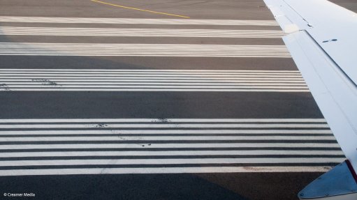 The wing of an aeroplane, with a runway in the background