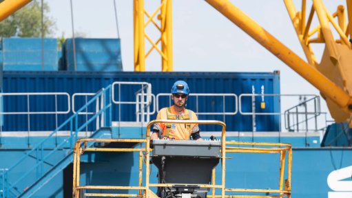 The above image depicts a worker operating a crane