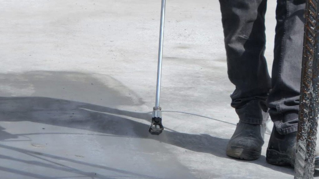 a man spraying a special concrete coating onto a concrete slab
