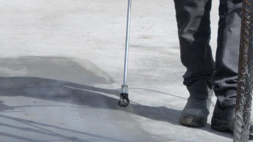a man spraying a special concrete coating onto a concrete slab