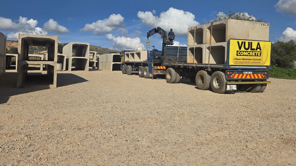 A large truck holding precast concrete pipes in a yard