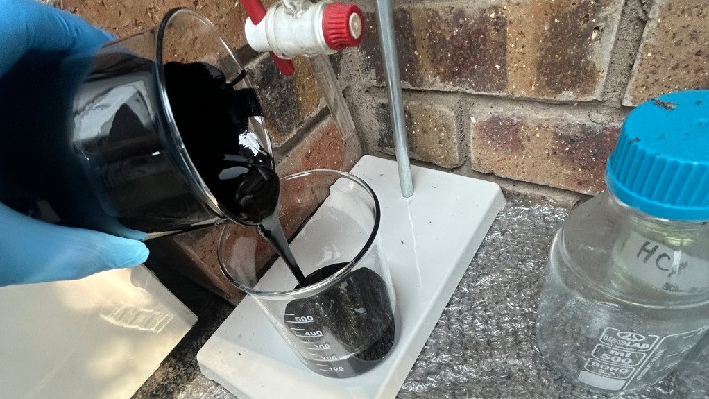 A science beaker with black liquid alternative fuel being poured into it